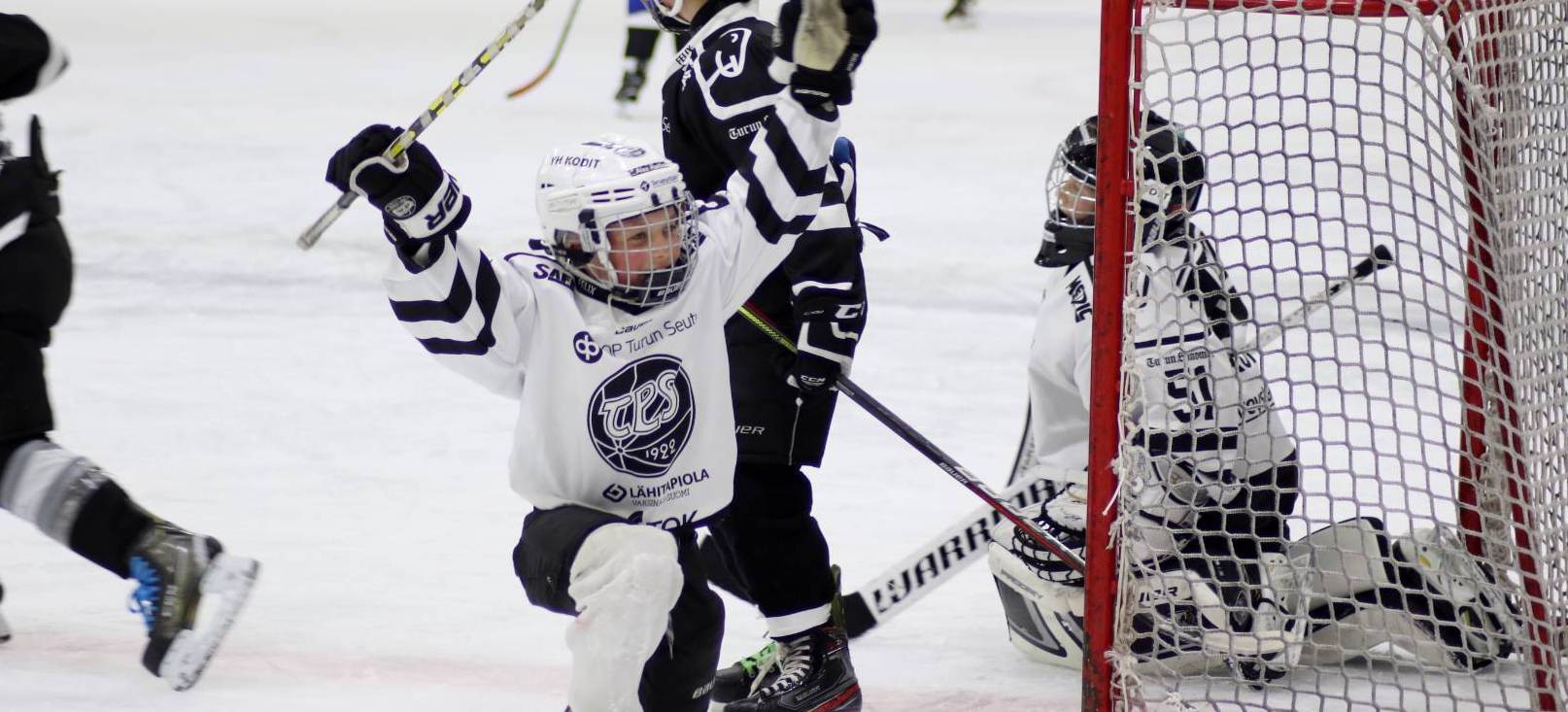 Alakouluikäinen TPS:n jääkiekkolijapoika tuulettaa polvillaan maalin jälkeen.